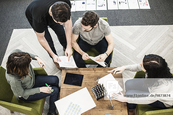 Vier Personen  die mit Farbstiften auf Papier an einem Tisch saßen  Kollegen bei einer Planungssitzung.