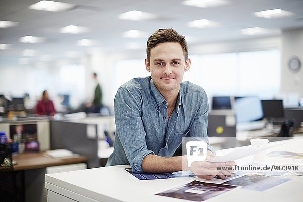 A man smiling and leaning forward on his desk.