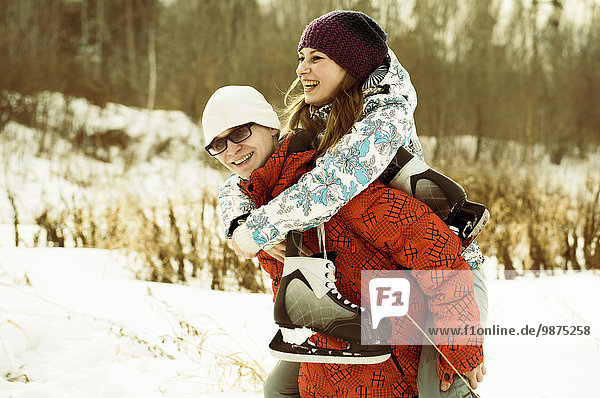 Caucasian couple carrying ice skates in snowy field