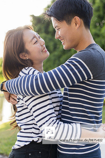 Smiling Korean couple hugging in park
