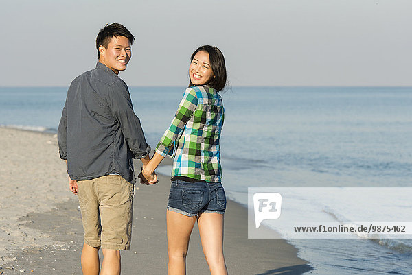 Korean couple walking on beach