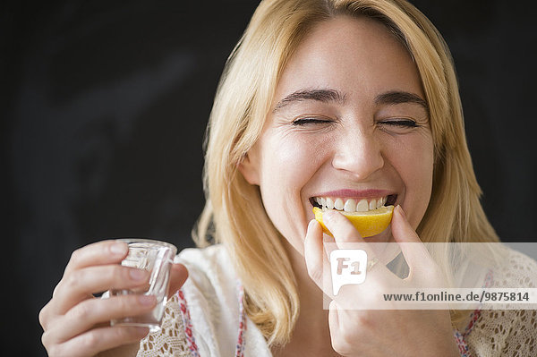 Caucasian woman eating lemon slice with liquor shot