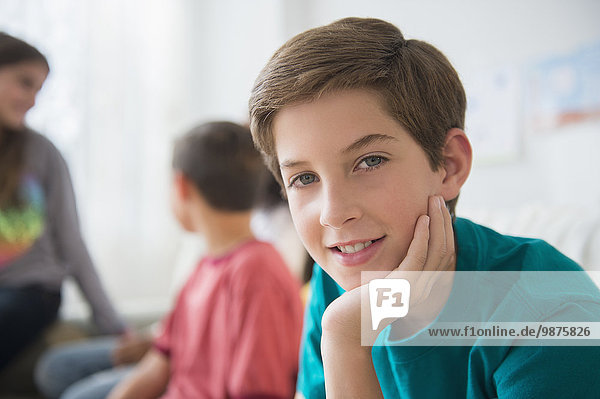 Smiling boy resting chin in hand in living room