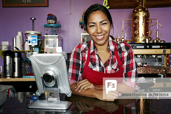 Hispanic barista smiling in coffee shop