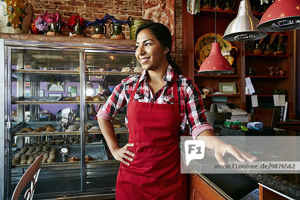 Hispanic waitress smiling in bakery