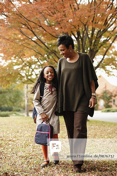African American mother walking with daughter in park