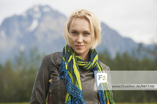 Woman with scarf stands in a meadow with Pioneer Peak in the background  Palmer  Mat-Su Valley  Southcentral Alaska
