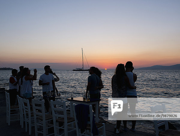 'Tourists gathered along the seafront in the Little Venice area of Mykonos Town to watch the sunset; Mykonos  Cyclades  Greek Islands  Greece'