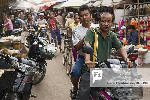 'Pedestrians and motorcycle riders on the street in Luh Market; Siem Reap  Cambodia'