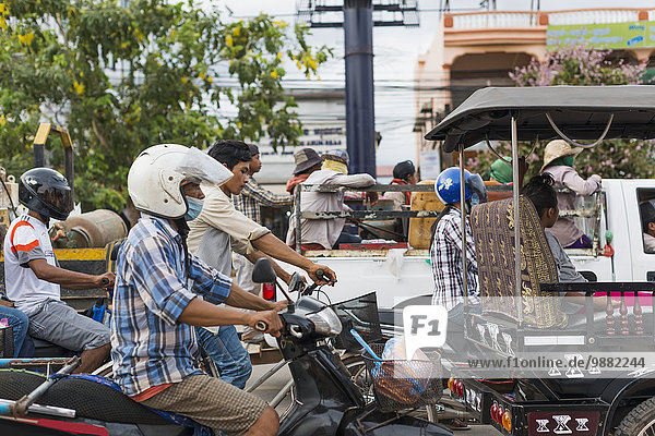 'Commuters on motorcycles on the busy street outside Luh Market; Siem Reap  Cambodia'