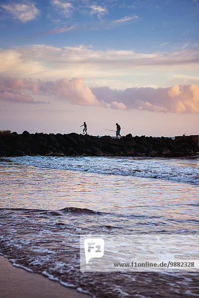 'A father and son fishing off the jetty at Pakala's; Kauai  Hawaii  United States of America'