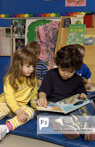 Four Year Old Girl And Five Year Old Boy  Reading A Book In A Classroom