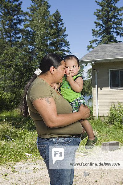 Native American Mother With Her Son Standing Outside In Front Of A Home.