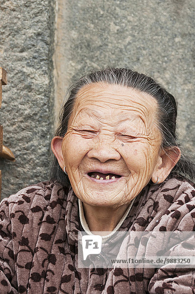 'An old Hakka minority's woman laughing in front of her house; Yongding  Fujian  China'