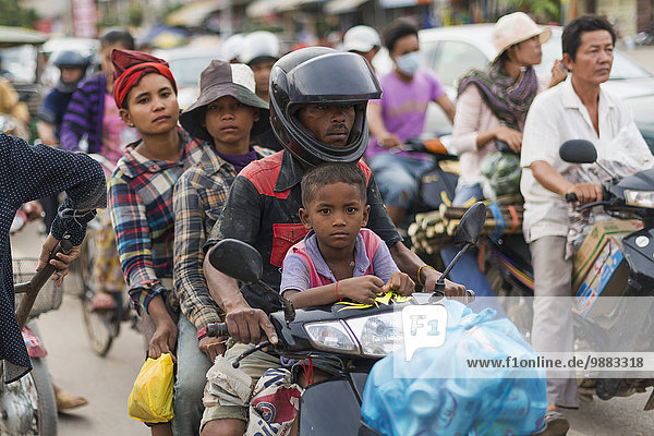 'Four people on a motorbike on a busy street outside Luh Market; Siem Reap  Cambodia'