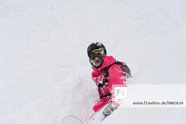 Snowboarder sitting in deep powder snow; St. Moritz  Graubunden  Switzerland