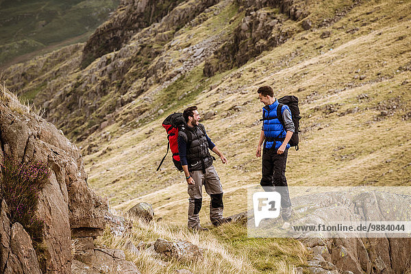 Zwei junge männliche Wanderfreunde beim Lachen und Plaudern  The Lake District  Cumbria  UK