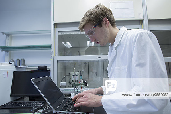 Männliche Wissenschaftler tippen auf Laptop im Labor