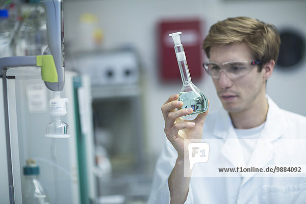 Männlicher Wissenschaftler beim Betrachten der Flasche im Labor
