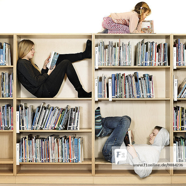 Siblings reading on book shelf