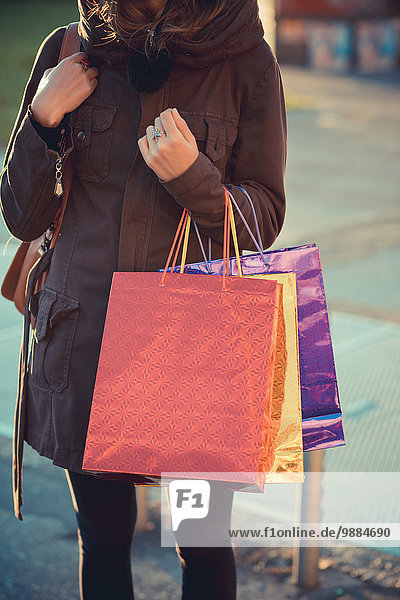 Schnappschuss einer erwachsenen Frau auf der Straße mit Einkaufstaschen