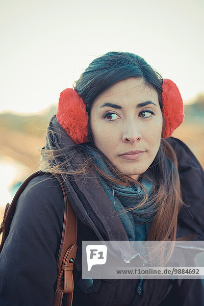 Mittlere erwachsene Frau mit roten Ohrenschützern im Park