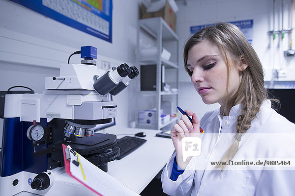 Wissenschaftlerin beim Lesen von Notizen auf der Zwischenablage im Labor