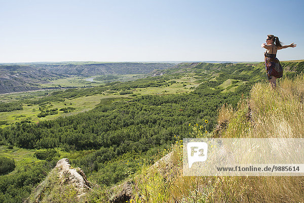 Woman enthusiastically enjoying the view of a green river valley; Alberta  Canada