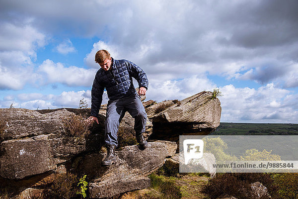Male teenage hiker stepping down rocks on Guise Cliff  Pateley Bridge  Nidderdale  Yorkshire Dales