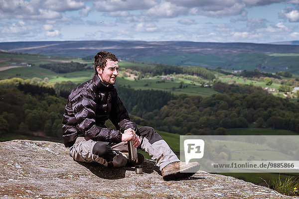 Young male hiker opening flask on top of Guise Cliff  Pateley Bridge  Nidderdale  Yorkshire Dales