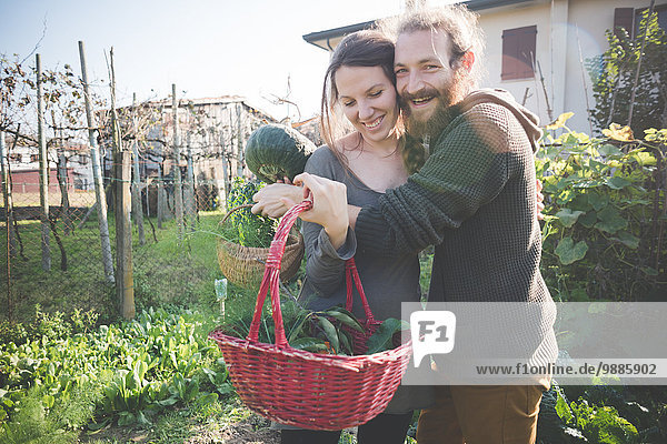 Young couple with basket of homegrown vegetables