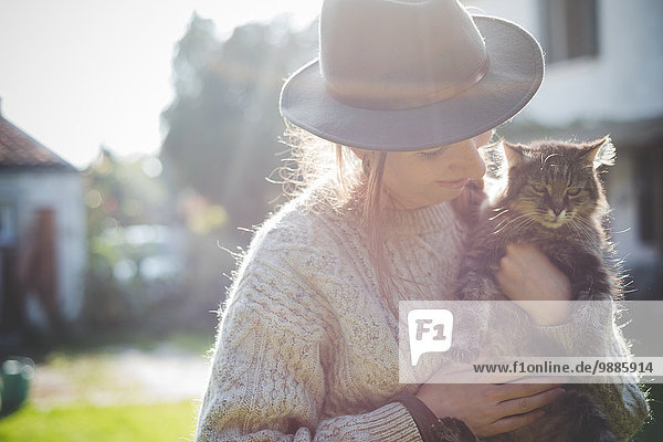 Young woman wearing hat  holding cat
