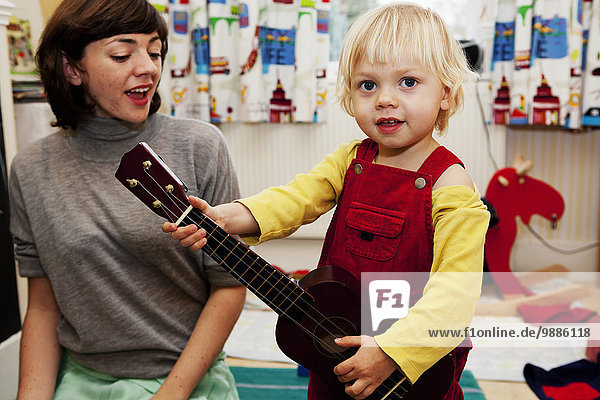 Junge spielt Spielzeuggitarre für Mutter