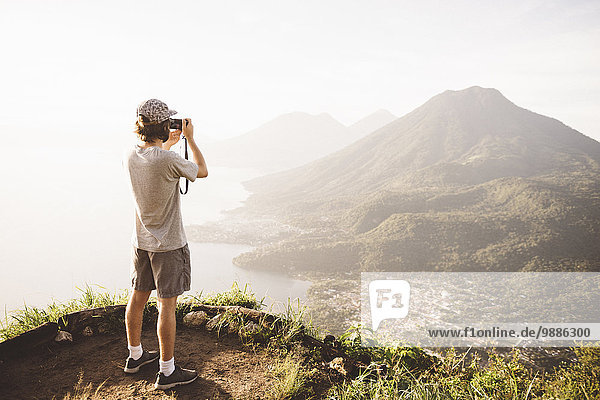Young man photographing at Lake Atitlan on digital camera  Guatemala