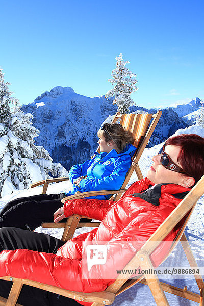 Two women in lounger in snow  Tegelberg  Ammergau Alps  Allgaeu  Bavaria  Germany  Europe