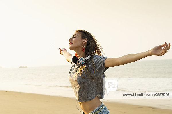 Young woman listening to music with her headphones on the beach; Xiamen  China