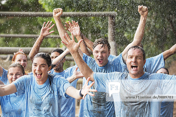 Begeistertes Team jubelt im Regen auf dem Bootcamp-Hindernisparcours