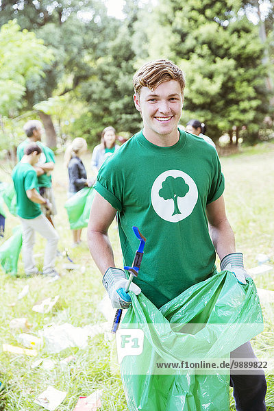 Porträt eines lächelnden Umweltschützers  der Müll aufsammelt.