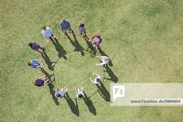 Overhead view of team connected in circle around plastic hoop
