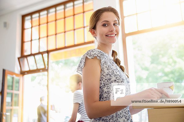 Junge Frau im Café hält Kaffeetasse.