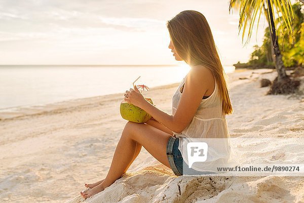 Junge Frau trinkt Kokosmilch am Strand von Anda  Provinz Bohol  Philippinen