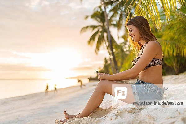Junge Frau beim Lesen von Smartphone-Texten am Strand von Anda  Provinz Bohol  Philippinen