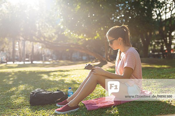 Junge Frau beim Lesen im Park  Manila  Philippinen