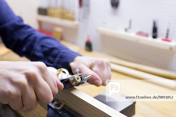 Close up of young female carpenters hands planing timber in workshop vice