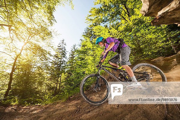 Young man downhill mountain biking in forest