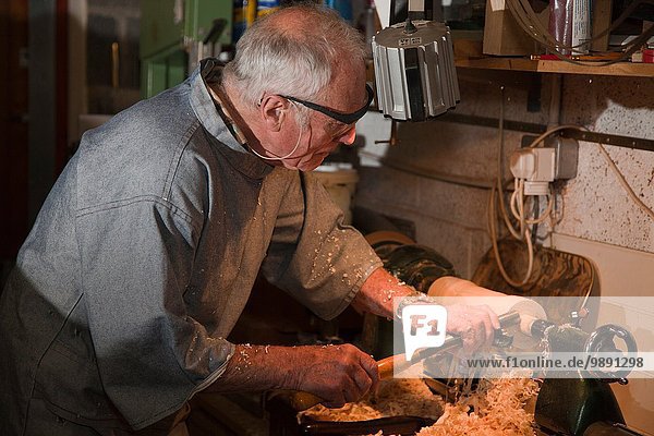 Älterer Mann  der mit Schreinerwerkzeugen Holz formt