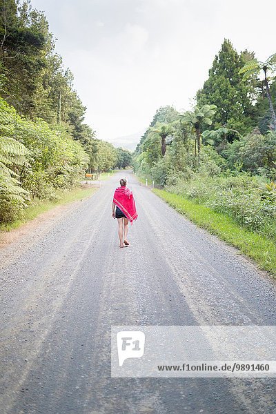 Woman walking away on straight road