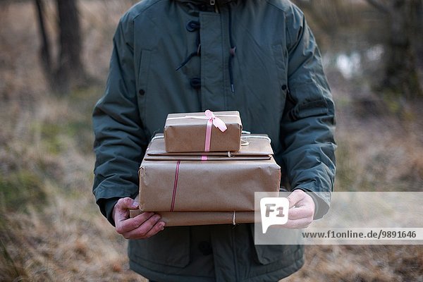 Cropped shot of gifts being carried through forest by young man
