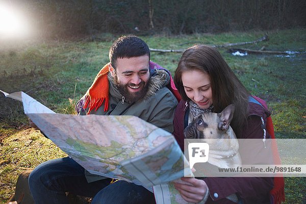 Young hiking couple reading map in woods