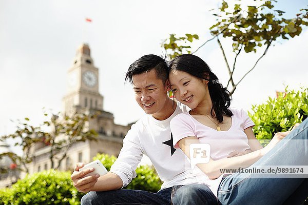 Tourist couple looking down at smartphone  The Bund  Shanghai  China